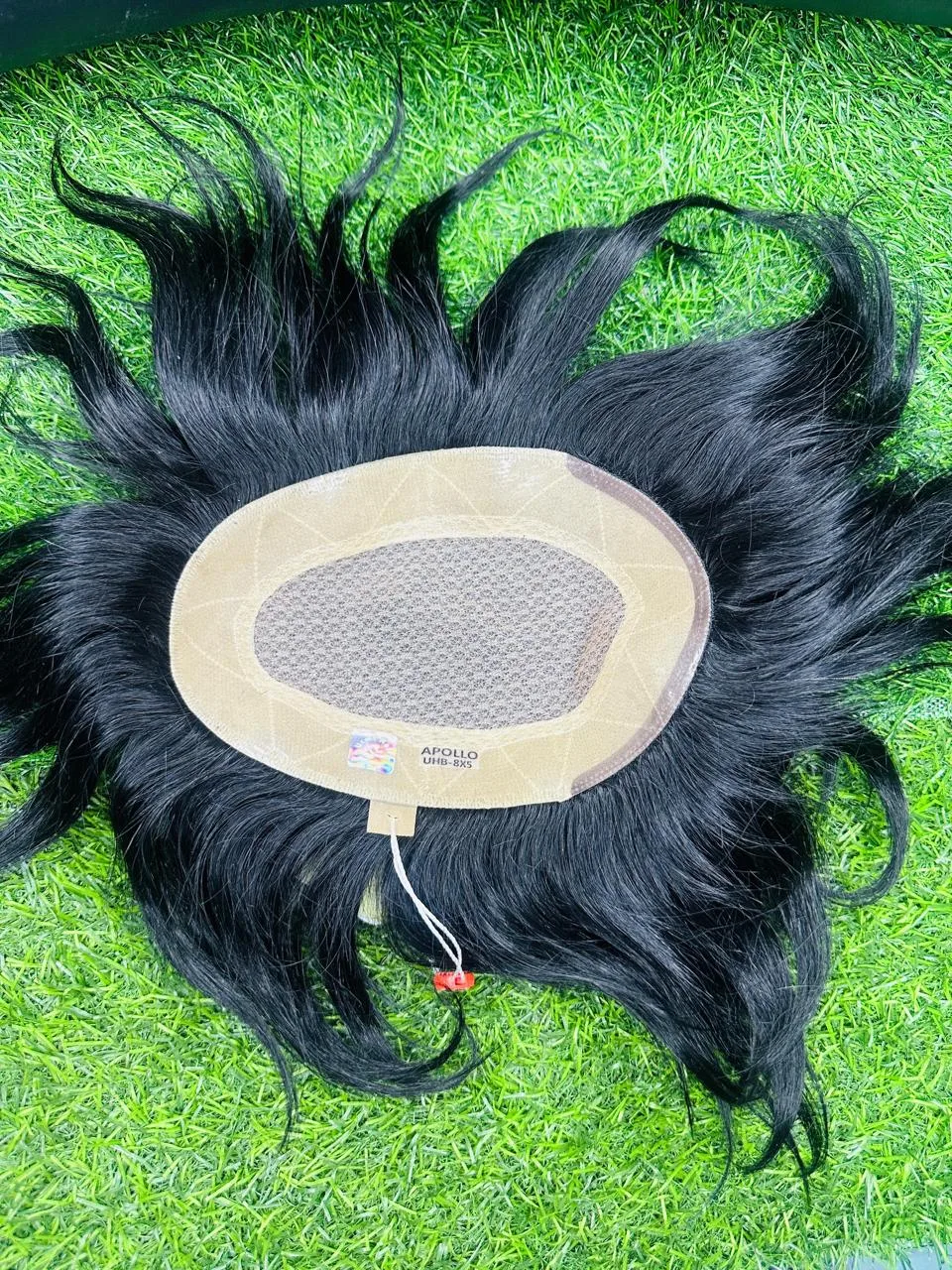 Oval hair system with a distinct centre panel and outer border on a green background